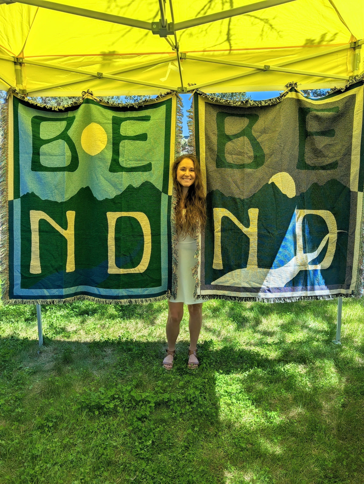 A woman in a white dress standing between two hanging blankets in a yellow tent